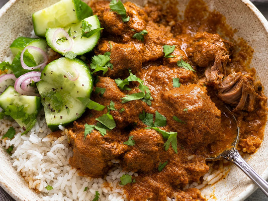 Curry d’agneau épicé servi avec du riz et du concombre frais