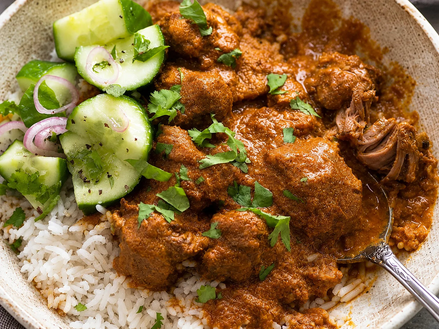 Curry d’agneau épicé servi avec du riz et du concombre frais