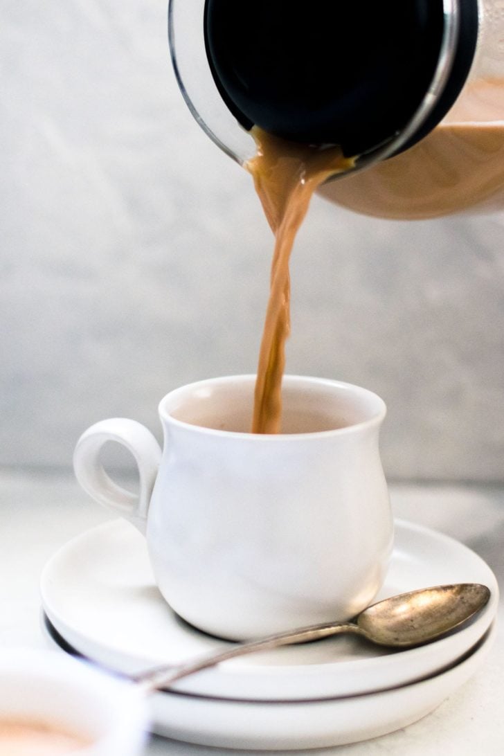 a cup of coffee sitting on a table next to a toilet 